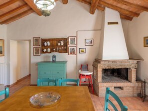 A dining area with a wooden table, teal chairs, a teal cabinet, and a brick fireplace. - Beautiful apartment for 4 people with WIFI, patio and pets allowed (Riparbella)