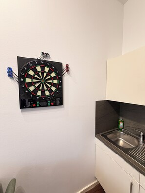 A dartboard mounted on a wall in a kitchen area with a sink and cabinets. - Fewo Mia | cozy city apartment for 4 people - ideal for families (Bamberg)