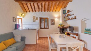 A cozy living area with a sofa, dining table, and kitchen in the background. - Lovely apartment for 5 people with WIFI, patio and pets allowed (Riparbella)