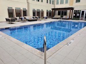 Una piscina con sillones de descanso y una pérgola.