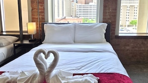 A hotel room with a bed, a red blanket, and a heart-shaped towel decoration. - Modern 1BR Sleeps 9, Downtown, Free Valet Parking (Dallas)