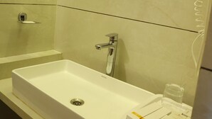 Un baño con un lavamanos blanco, un espejo y un vaso de agua sobre la encimera.