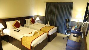 Una habitación de hotel con dos camas, un escritorio, una silla y un televisor.