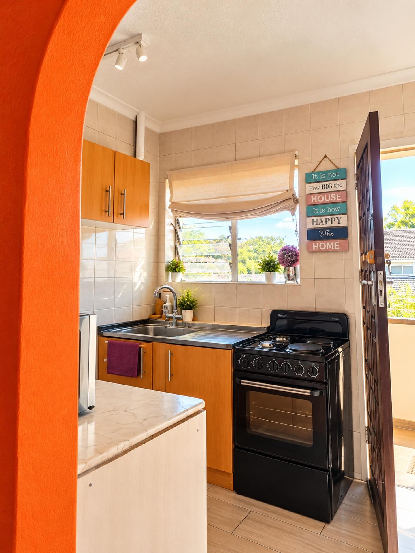 A kitchen with wooden cabinets, a black stove, and a window with a view of greenery.