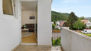 Un balcon donnant sur un quartier résidentiel, un mur blanc et une porte menant à une pièce intérieure.