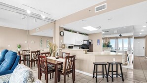 Eine moderne Küche mit Kochinsel, Essbereich mit Stühlen und ein Wohnzimmer mit Sofa.