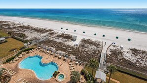 Luftaufnahme eines Strandrausorts mit Schwimmbad, Liegestühlen und einem Strandweg.