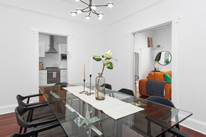 Un espace repas moderne avec une table en verre, des chaises et un vase rempli de fleurs.