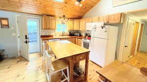 Una cocina con armarios de madera, una mesa de comedor de madera y un refrigerador blanco.