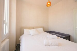 Una camera d'albergo con un letto, una finestra, un termosifone e un lampadario.