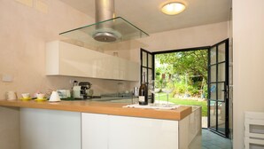 Eine moderne Küche mit Kochinsel, weißen Schränken und einer Dunstabzugshaube mit Glasfront.