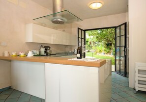 Una cucina moderna con isola centrale, mobili bianchi e cappa aspirante con vetro.