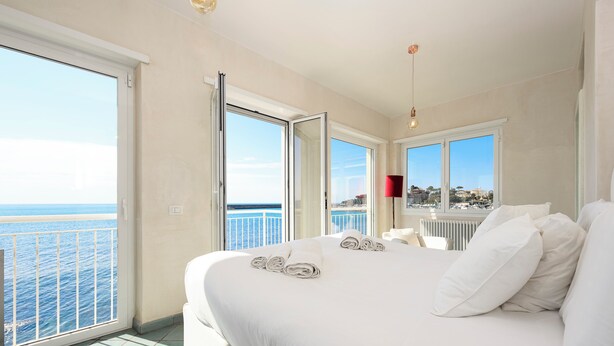 Ein Hotelzimmer mit einem großen Bett, Meerblick und einem Balkon.