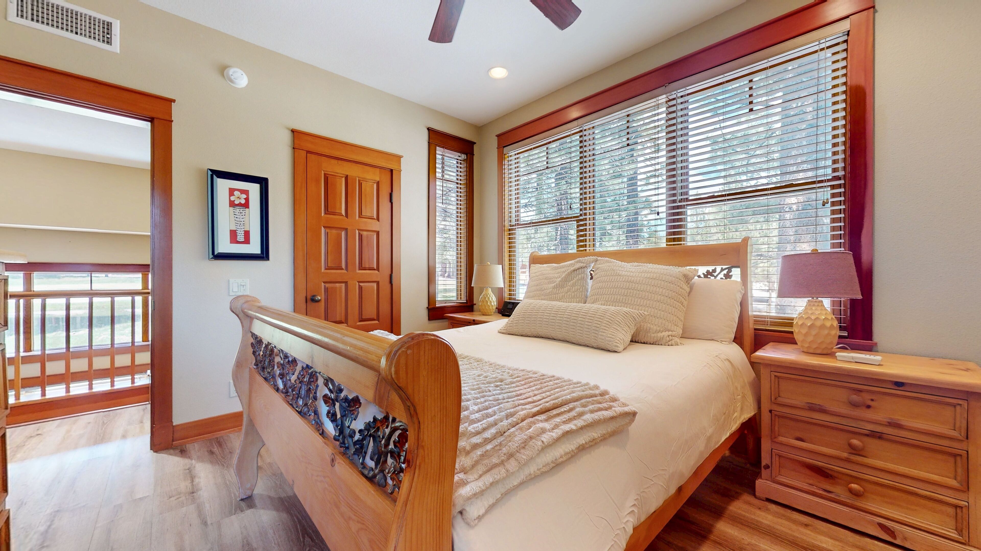 A bedroom with a wooden bed, a nightstand, a dresser, and a window with blinds.