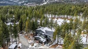 Una cabaña en la montaña rodeada de un bosque denso y terreno cubierto de nieve.