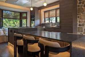 A modern kitchen with a central island, bar stools, and large windows.