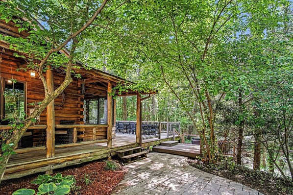 A wooden cabin with a porch, surrounded by trees.