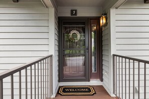 Una entrada de casa con una puerta oscura, un felpudo y un letrero con el número 3 sobre la puerta.
