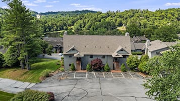 A large building with a parking lot, surrounded by trees and hills.