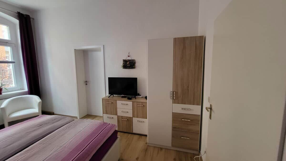 Ein Schlafzimmer mit einem Bett, einem Kleiderschrank, einem Fernseher und einem Schreibtisch.