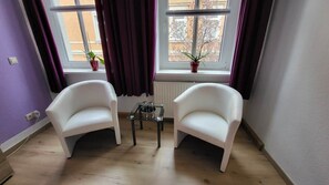 A room with two white armchairs, a small table, and a window with curtains. - Beautiful Vacation Rental in Dresden (Dresden)