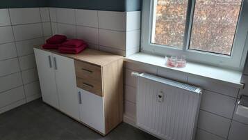 Eine Küche mit Fenster, Heizkörper und einem Schrank mit Schubladen.