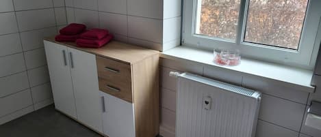 A kitchen with a window, a radiator, and a cabinet with drawers.