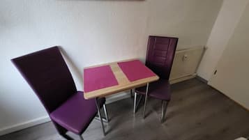 A small room with a wooden table and two purple chairs.