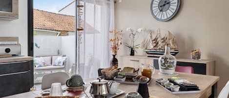 A dining area with a table set for breakfast, a clock on the wall, and a view of the outside.