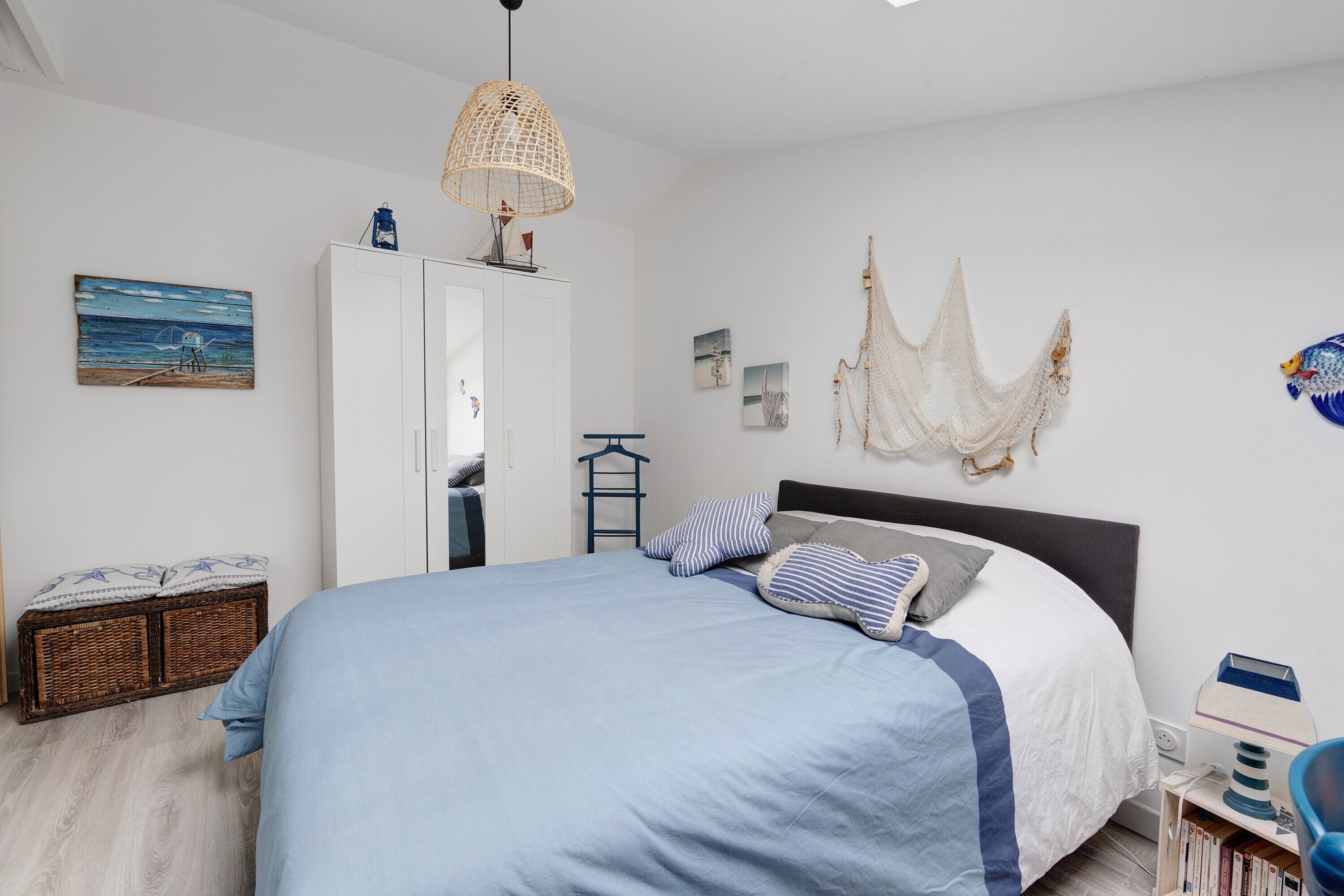 Une chambre à coucher comprenant un lit, une armoire, un luminaire suspendu et des œuvres d’art mural.