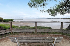 Un banc en bois donnant sur une plage, avec une clôture en bois et une vue sur la mer.