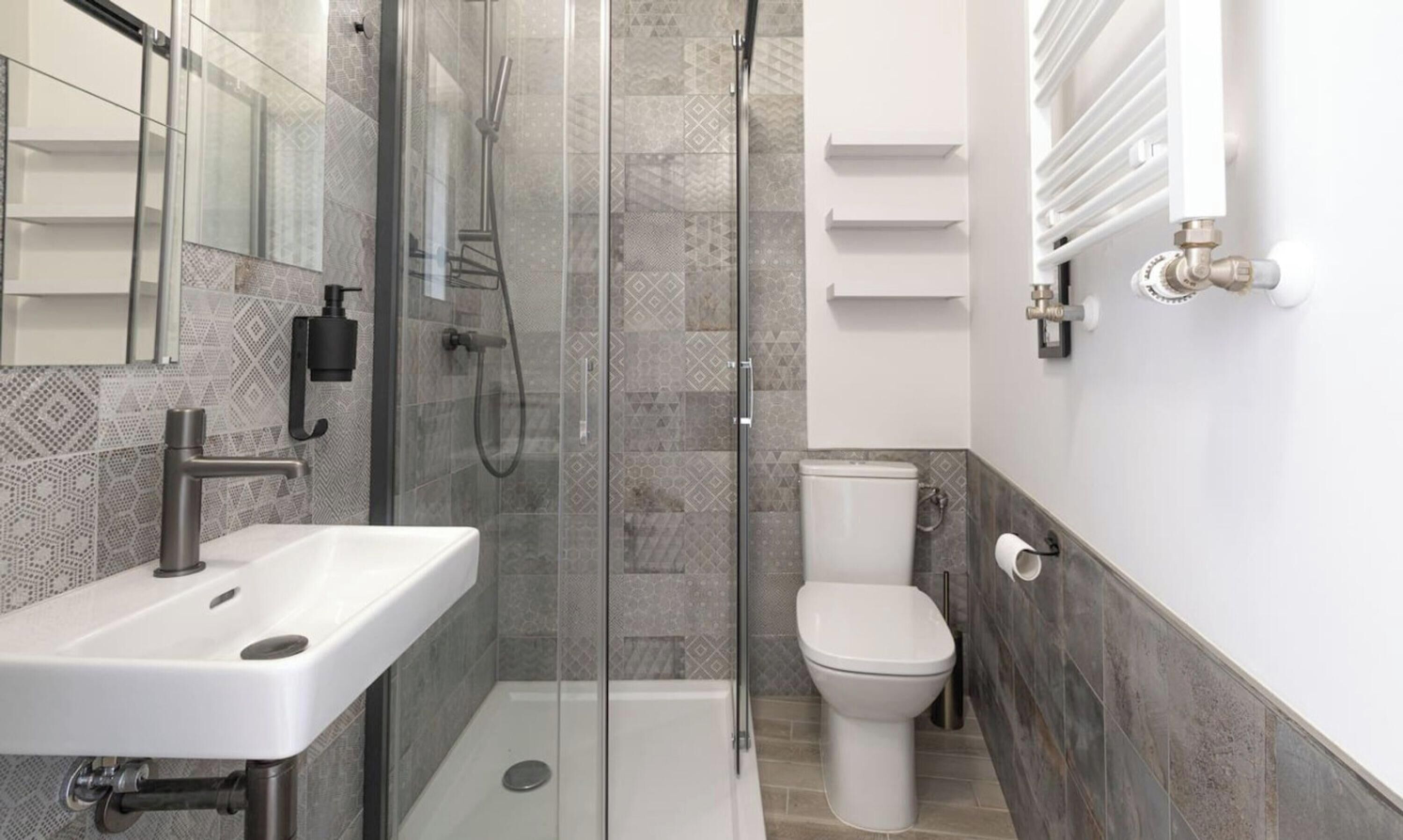 Une salle de bain moderne avec une douche à parois de verre, un lavabo blanc et des toilettes.
