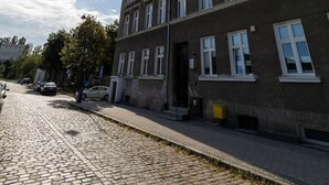 A multi-story building with a cobblestone street in front, featuring a row of windows and a visible entrance. - Verde 5 Gda sk Pok j z Azienk Blisko Centrum (Gdańsk)