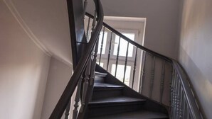 Un escalier avec des balustres en bois et une main courante, menant à une porte située en haut.