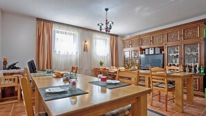 A dining area with a wooden table set for four, surrounded by chairs. There is a chandelier above the table, and a cabinet with glass doors to the right. - Haus Anna in Rastovača - Plitvicer Seen / Haus Anna in Rastovača - Einzelzimmer ED1 (Plitvicka Jezera)