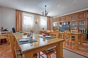 Ein Essbereich mit einem Holztisch, gedeckt für vier Personen, umgeben von Stühlen. Über dem Tisch hängt eine Chandelier, und rechts befindet sich ein Schrank mit Glastüren.