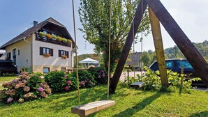 A house with a garden, a swing, and a parked car. - Haus Anna in Rastovača - Plitvicer Seen / Haus Anna in Rastovača - Einzelzimmer ED1 (Plitvicka Jezera)