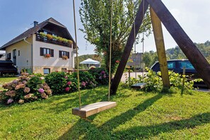 Ein Haus mit Garten, einer Schaukel und einem geparkten Auto.