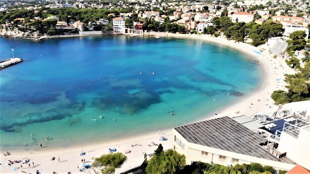 Un pueblo costero con playa, aguas cristalinas y edificios.