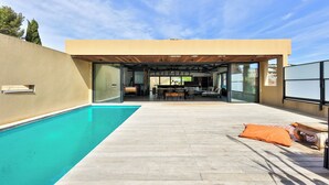 Una casa moderna con piscina, un porche cubierto y vistas al paisaje.