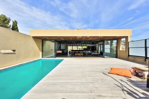 Une maison moderne dotée d’une piscine, d’un patio couvert et offrant une vue sur le paysage.