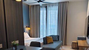 A modern hotel room with a bed, seating area, dining table, and a ceiling fan. - Cozy 1-bedroom studio in peaceful Langkawi with AC and gym access, kitchen (Langkawi)