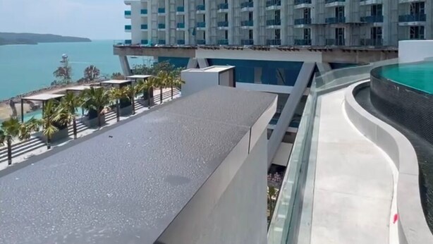 A modern hotel with a pool, a view of the sea, and a construction crane in the background. - Cozy 1-bedroom studio in peaceful Langkawi with AC and gym access, kitchen (Langkawi)