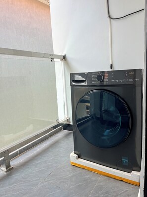 A front-loading washing machine in a room with a tiled floor and a glass door. - Spacious & Convenient 1br Kisaasi,Kampala with AC & Power backup (Kampala)
