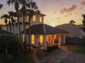 Ein zweistöckiges Haus mit einer überdachten Terrasse, einem Pool und einem gepflegten Rasen.