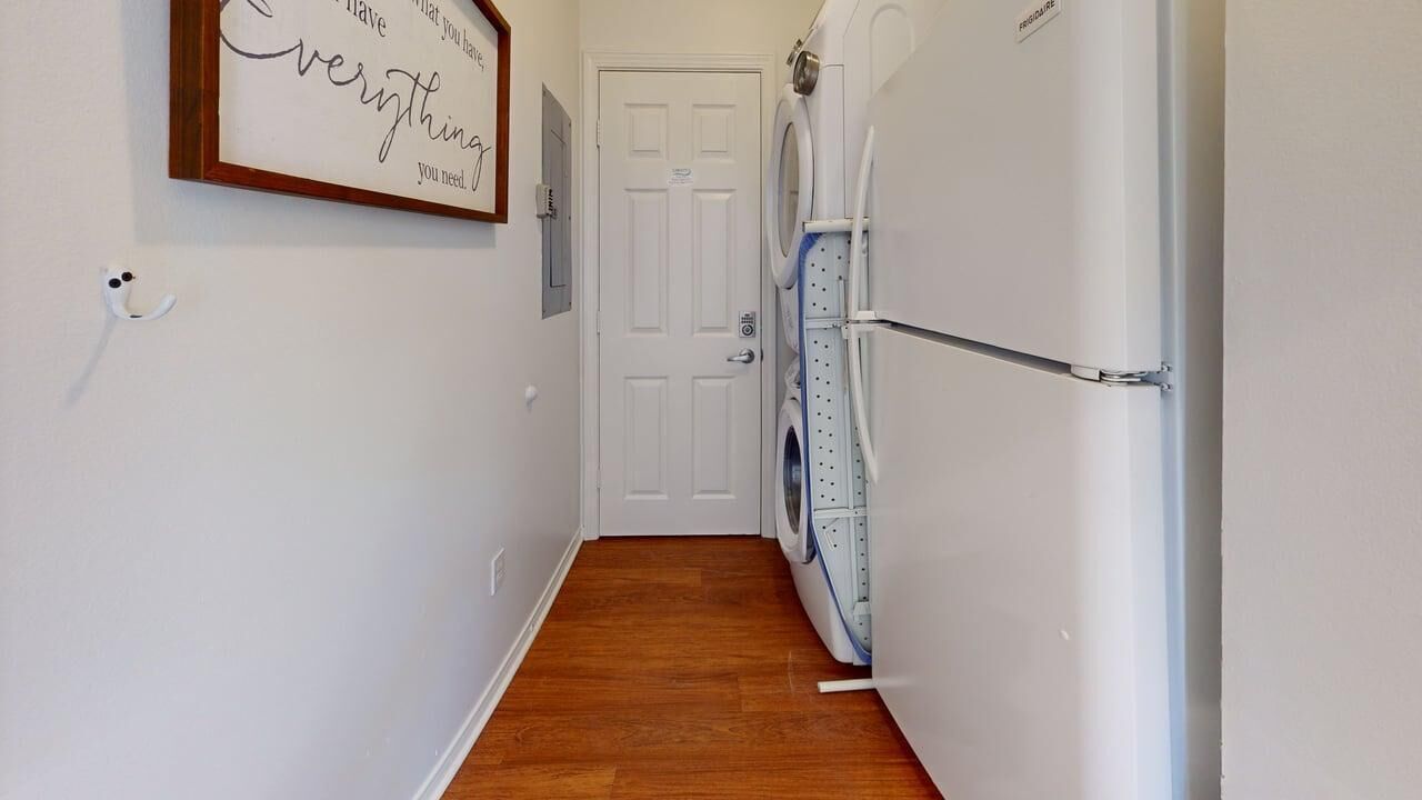 A laundry room with a washing machine, dryer, and a door leading to another room.