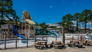Vandland med rutsjebaner, picnicborde og en legeplads i træ.