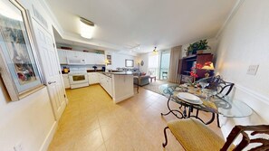 A spacious kitchen with white cabinets, a dining area with a glass table, and a balcony with a view. - Tidewater 406 | New Listing! Gulf Front Views |Walk to Pier Park (Panama City Beach)