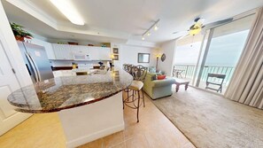 Eine moderne Küche mit Granitarbeitsplatte, ein Essbereich mit Barhocker und ein Balkon mit Blick.