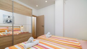 A hotel room with a bed, a mirror, a wooden door, and a light fixture. - Quiet apartment with pool, terrace and parking in Crikvenica (Crikvenica)